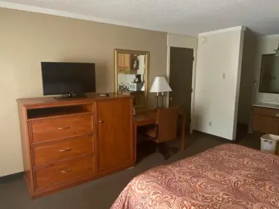 a bedroom with a bed and a dresser with a television on it at Snowshoe Motel in Frisco