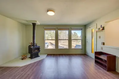 an empty living room with a wood burning stove at 17 Mi to Town Peaceful Golden Cabin! in Golden