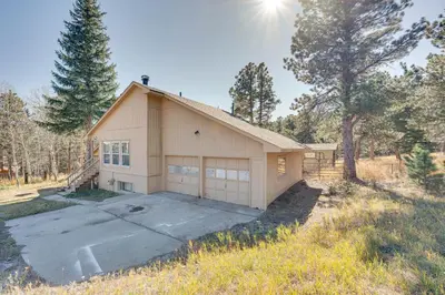 a house with a garage in the middle of a field at 17 Mi to Town Peaceful Golden Cabin! in Golden
