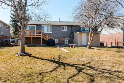 a house with a deck and a yard with two trees at 4 Bedrooms and 5 Beds with Game Room Only 5 min Drive to College and Perfect for Family's in Boulder
