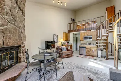 a living room with a table and a fireplace at Private Balcony and Mtn Views Granby Studio! in Granby