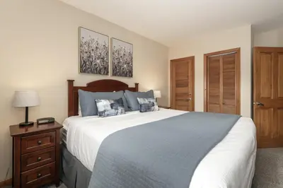 a bedroom with a large bed with blue pillows at Premium Unit 1327 - 1 Bedroom - Zephyr Mountain condo in Winter Park