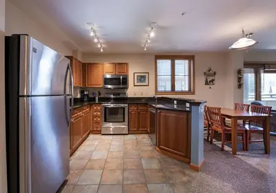 a kitchen with a stainless steel refrigerator and a table at Premium Unit 1327 - 1 Bedroom - Zephyr Mountain condo in Winter Park