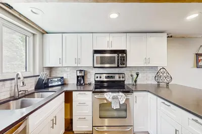 a kitchen with white cabinets and stainless steel appliances at Fraser's Mountain Fantasy in Fraser