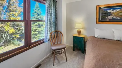 a bedroom with a bed and a chair and a window at Manorhouse Hideaway in Dillon
