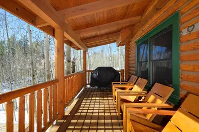 a porch of a log cabin with wooden chairs at 980 Mulligan in Fraser