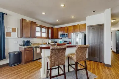 a kitchen with wooden cabinets and two bar stools at Silver Sage Sanctuary in Granby