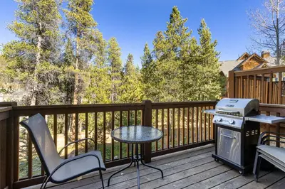 a balcony with a grill and a table and chairs at 1849 The Seasons townhouse in Keystone