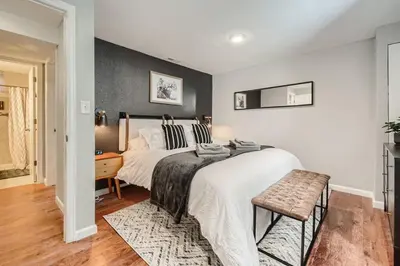 a bedroom with a large bed and a chair at Adorable 2-Bedroom Modern Basement in Denver
