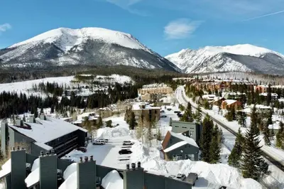a resort in the snow with mountains in the background at Cozy Ski Condo + Hot Tub + Fireplace + Heated Pool in Silverthorne