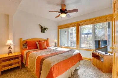 a bedroom with a bed and a ceiling fan at half Mi to Granby Ranch Townhome with Fireplace! in Granby