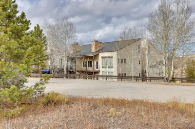 a large stone house with a fence in front of it at half Mi to Granby Ranch Townhome with Fireplace! in Granby