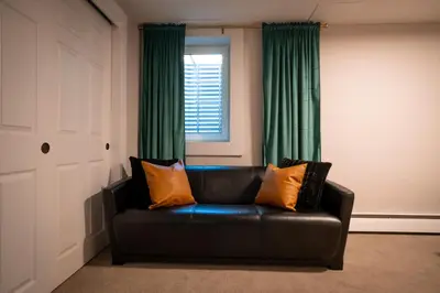 a black leather couch in a room with green curtains at Rocky Mountain Haven-Modern 2BD, 1BA Basement Retreat in Lakewood in Lakewood