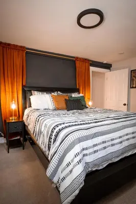 a bedroom with a large bed with orange curtains at Rocky Mountain Haven-Modern 2BD, 1BA Basement Retreat in Lakewood in Lakewood