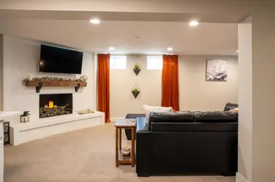 a living room with a black couch and a fireplace at Rocky Mountain Haven-Modern 2BD, 1BA Basement Retreat in Lakewood in Lakewood