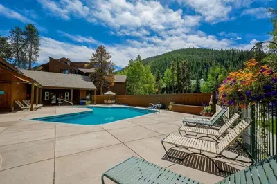 a patio with a pool and some chairs and a fence at 1076 Wild Irishman condo in Keystone