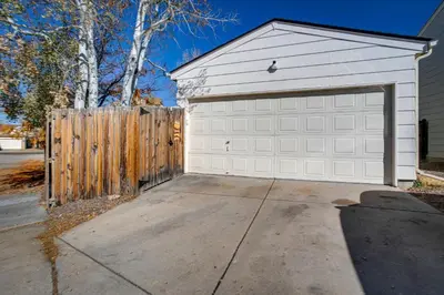 a white garage door with a wooden fence at Patio, Grill, Yard Pet-Friendly Denver Home! in Aurora