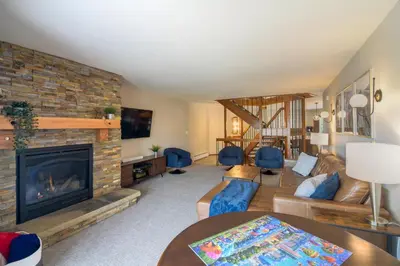 a living room with a fireplace and blue chairs at Winter Park Townhome with Hot Tub, Half Mi to Dtwn! in Winter Park