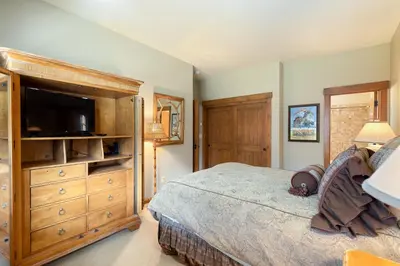 a bedroom with a bed and a dresser with a television at 66 Thackwell Lane townhouse in Keystone
