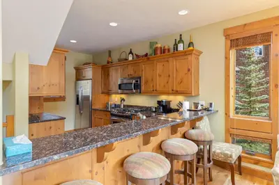 a kitchen with wooden cabinets and a counter with bar stools at 66 Thackwell Lane townhouse in Keystone