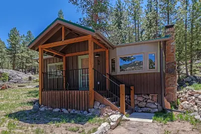 a tiny house in the woods with a porch at Niwot Cabin - Stay in Rocky Mountain National Park - Estes Park - NEW LISTING - 22-ZONE3298 cabin in Estes Park