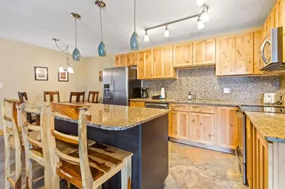 a kitchen with wooden cabinets and a large island with bar stools at Rocky Mountain Escape with Vista View - Wildernest in Silverthorne