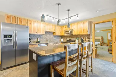 a kitchen with wooden cabinets and a stainless steel refrigerator at Rocky Mountain Escape with Vista View - Wildernest in Silverthorne