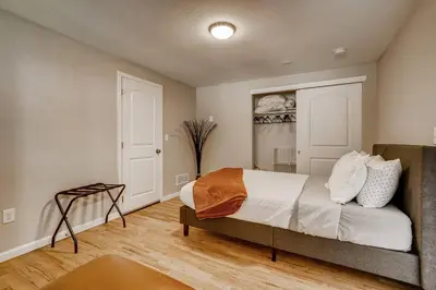 a bedroom with a bed with white sheets and an orange blanket at Close to Denver & Golden - Perfect for Groups in Arvada