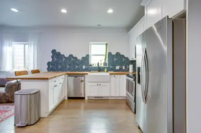 a kitchen with white cabinets and a stainless steel refrigerator at Cozy and Pet-Friendly Home - 3 Mi to Downtown Denver in Denver