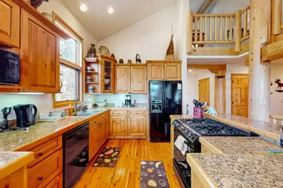 a kitchen with wooden cabinets and a black refrigerator at Sundance Mountain Retreat in Fraser