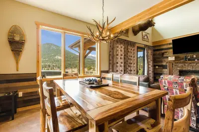 a dining room with a wooden table and a large window at Show Me Mountain Views -- 20-NCD0130 home in Estes Park