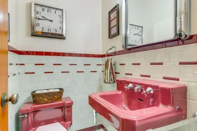 a bathroom with a red sink and a clock on the wall at Charming Idaho Springs Retreat on Chicago Creek! in Idaho Springs