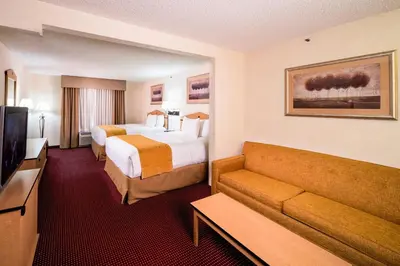 a hotel room with two beds and a couch at AmericInn by Wyndham Denver Airport in Denver