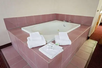 a bathroom with a bath tub with two towels at AmericInn by Wyndham Denver Airport in Denver