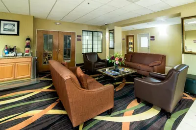 a waiting room with couches and chairs and a table at AmericInn by Wyndham Denver Airport in Denver