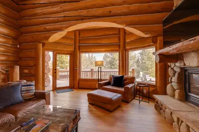 a living room with a fireplace in a log cabin at Fraser Chalet with Hot Tub and Mountain Views in Fraser