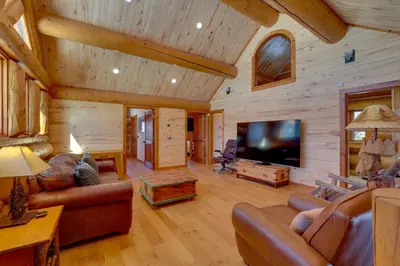 a living room in a log cabin with a flat screen tv at Fraser Chalet with Hot Tub and Mountain Views in Fraser