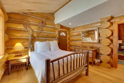 a bedroom with a bed in a log cabin at Fraser Chalet with Hot Tub and Mountain Views in Fraser