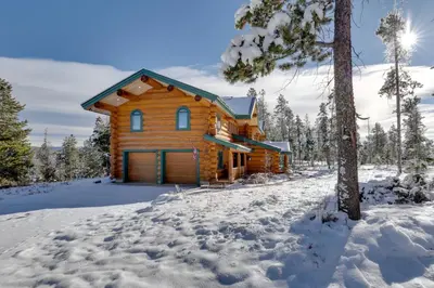 a log cabin in the woods in the snow at Fraser Chalet with Hot Tub and Mountain Views in Fraser