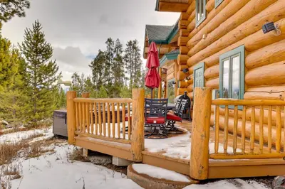 a log cabin deck with two chairs and an umbrella at Fraser Chalet with Hot Tub and Mountain Views in Fraser