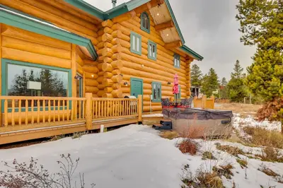 a log cabin with snow on the porch at Fraser Chalet with Hot Tub and Mountain Views in Fraser