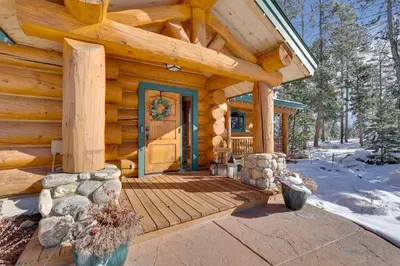 a log cabin with a deck in the snow at Fraser Chalet with Hot Tub and Mountain Views in Fraser