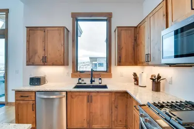 a kitchen with wooden cabinets and a sink and a window at Winter Park Retreat Balcony, Hot Tub and Fireplace! in Fraser