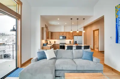 a living room with a couch and a kitchen at Winter Park Retreat Balcony, Hot Tub and Fireplace! in Fraser