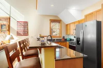 a kitchen with a stainless steel refrigerator and wooden cabinets at Antlers Gulch Townhomes #71 in Keystone