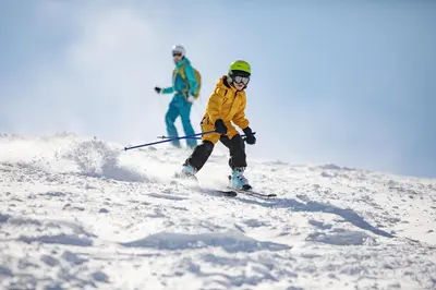 two people are skiing down a snow covered slope at Hi Country Haus - 10-18,,, condo in Winter Park