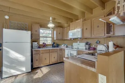 a kitchen with wooden cabinets and a white refrigerator at Red Feather Lakes Cabin with Deck and Views! in Red Feather Lakes