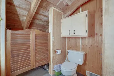 a bathroom with a toilet and a wooden wall at Red Feather Lakes Cabin with Deck and Views! in Red Feather Lakes