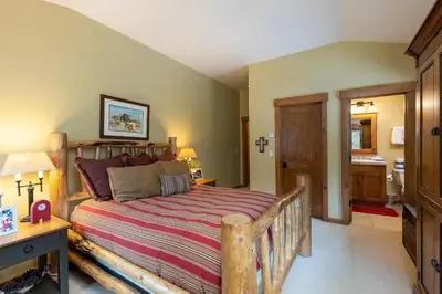 a bedroom with a wooden bed and a bathroom at 45 Thackwell Lane townhouse in Keystone