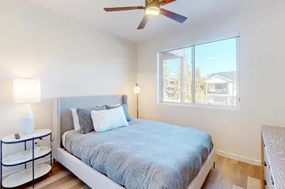 a bedroom with a bed with a ceiling fan and a window at Mellow on Meadow Mile in Fraser